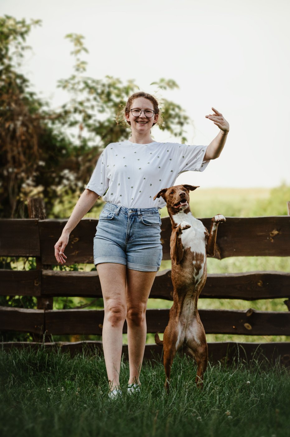 Bettina dancing with her dog by a wooden fence